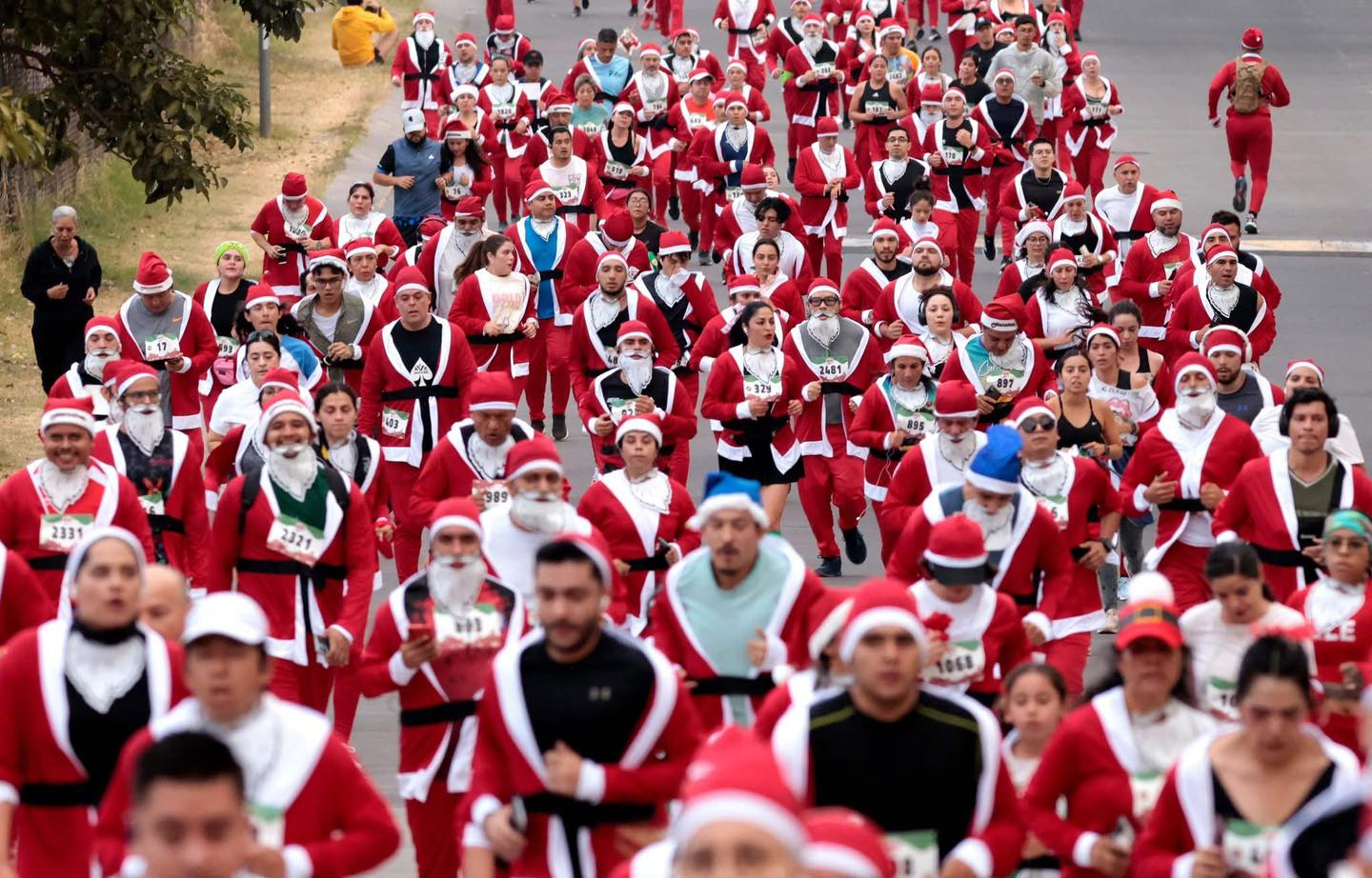 Corredores vestidos de Papá Noel participan en la carrera navideña anual “Run Santa Run”.